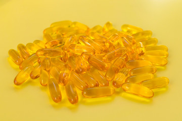 
Vitamins. Useful omega 3 on a yellow background. Fish oil capsules close-up.