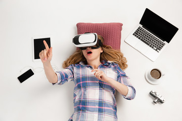 Young caucasian woman using devices, gadgets isolated on white studio background. Concept of modern...