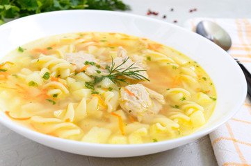 Dietary chicken soup with fusilli in a white bowl on a light background