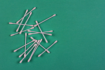cotton swabs are scattered on a green background close up view from above with a copy space