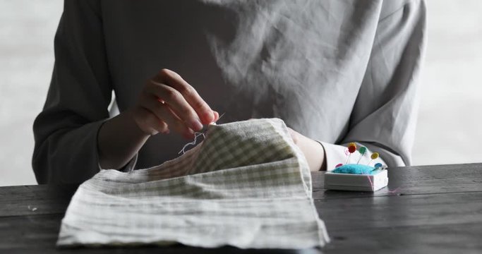 部屋の中で裁縫をする若い女性の手元