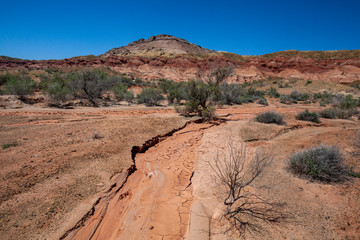 Takyr, a dried-up trace from a past mudflow. Cracked clay soil in the form of shards against the background of colored hills in Kazakhstan.
