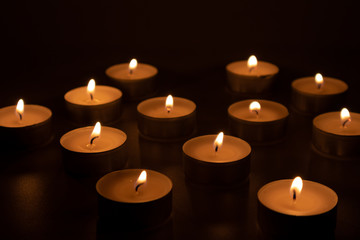 Fototapeta na wymiar Burning candles in the dark, feeling of sadness and sorrow
