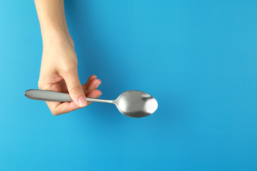 Top view woman hand holding spoon on blue background