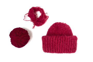 Isolated hat and yarn balls. Bright red knitted hat on the white background. Flat lay. Top view. Knitting with love.