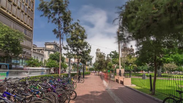 Red cycling track in the Jose Larco avenue and bicycle parking timelapse hyperlapse in Miraflores, Lima Peru. Central park on the right side and traffic on the street