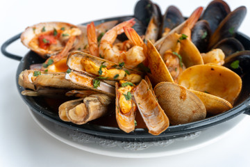 Sauteed shellfish and seafood in a black pan on a white background 