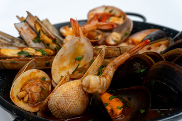 Sauteed shellfish and seafood in a black pan on a white background 