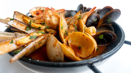 Sauteed shellfish and seafood in a black pan on a white background 