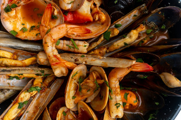 Sauteed shellfish and seafood in a black pan on a white background 