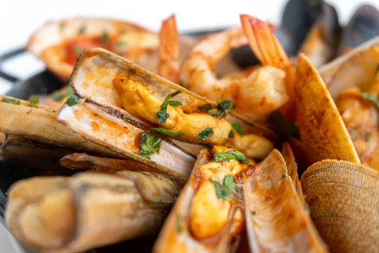 Sauteed shellfish and seafood in a black pan on a white background 