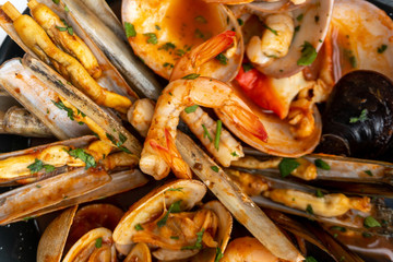 Sauteed shellfish and seafood in a black pan on a white background 