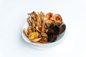 Sauteed shellfish and seafood in a white plate on a white background