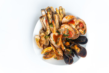Sauteed shellfish and seafood in a white plate on a white background
