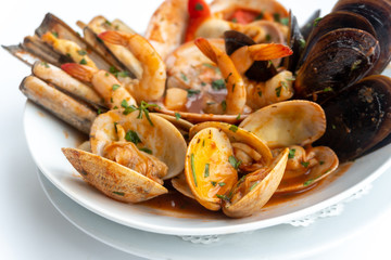 Sauteed shellfish and seafood in a white plate on a white background