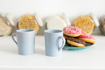 Two coffee cups and donuts in the kitchen