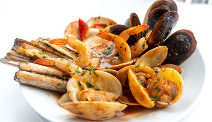 Sauteed shellfish and seafood in a white plate on a white background