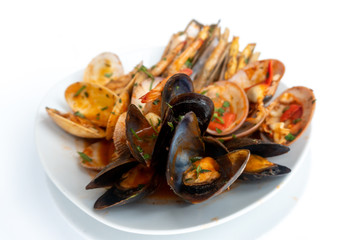 Sauteed shellfish and seafood in a white plate on a white background