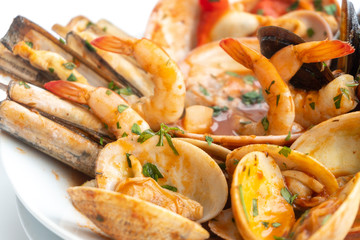 Sauteed shellfish and seafood in a white plate on a white background