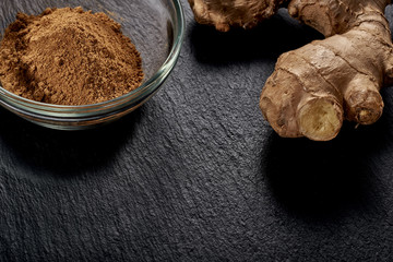 Ground ginger in a plate. Ginger root on a black background. side view. volume ripe product. macro photo. Against viruses and diseases.