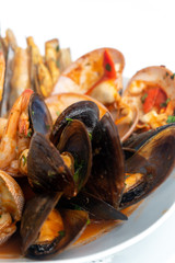Sauteed shellfish and seafood in a white plate on a white background