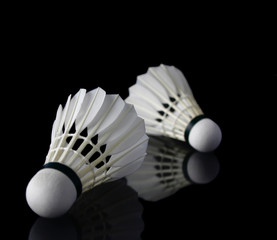 Shuttlecocks against black on reflective surface