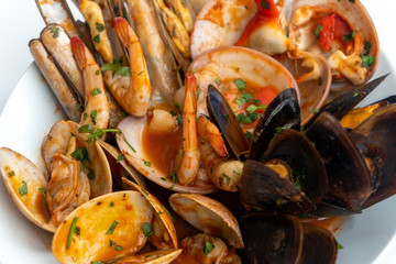 Sauteed shellfish and seafood in a white plate on a white background