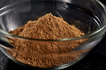 Ground ginger in a plate on a black background. side view. sharp powder. macro photo. Against viruses and diseases.