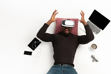 Young african-american man using devices, gadgets isolated on white studio background. Concept of...
