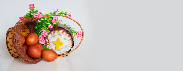 Easter cake, red chicken eggs in a basket and flowers on a white background: happy Easter, banner