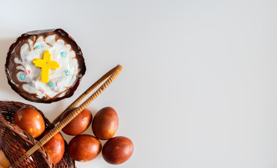 Easter cake and red chicken eggs in a basket on a white background: happy Easter, top view