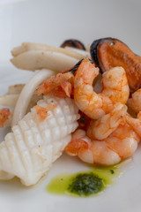 Fancy FISH AND SEAFOOD with soup on a white plate with a white background