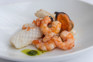 Fancy FISH AND SEAFOOD with soup on a white plate with a white background