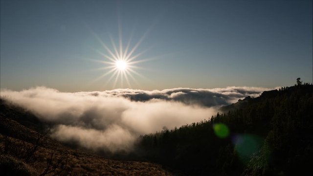 Time Lapse Of Wavey Rolling Clouds In Mountains Of Tenerife With Sun Shining Against Blue Skies. Locked Off 