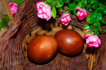 Red chicken Easter eggs in a basket and flowers: happy Easter