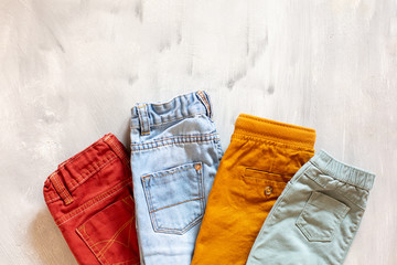 Casual clothes for a boy on a light background. Colored jeans top view.