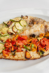 Baked fish with vegetables, zucchini and tomatoes