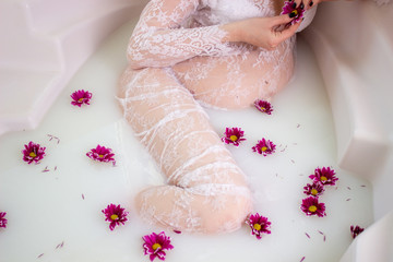 young pregnant woman in a bathtub filled with milk and flowers