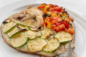 Baked fish with vegetables, zucchini and tomatoes