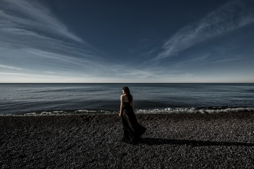
girl stands on the seashore in a black dress