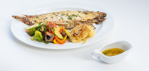 Sole meunière fish with grilled vegetables and caramelized onions on a white plate with white background. LENGUADO MENIER