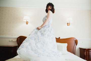 Fototapeta premium Beautiful bride wearing fashion wedding dress with feathers with luxury delight make-up and hairstyle, studio indoor photo shoot