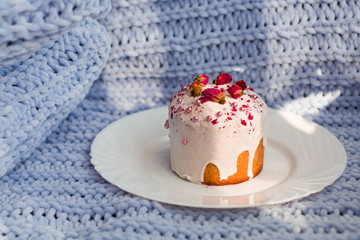 Cake with flowers, beads and nuts. Blue knitted plaid. Cozy Easter, spring still life scene. The concept of the Easter holidays and decor. 