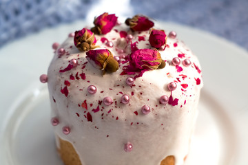 Cake with flowers, beads and nuts. Blue knitted plaid. Cozy Easter, spring still life scene. The concept of the Easter holidays and decor. 