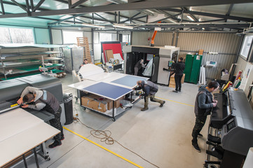 Large group of technicians works in printing printshop press hall