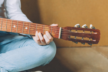 Stay Home Stay Safe. Young woman sitting at home and playing guitar, hands close up. Teen girl...