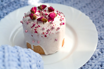 Cake with flowers, beads and nuts. Blue knitted plaid. Cozy Easter, spring still life scene. The concept of the Easter holidays and decor. 