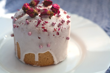 Cake with flowers, beads and nuts. Blue knitted plaid. Cozy Easter, spring still life scene. The concept of the Easter holidays and decor. 