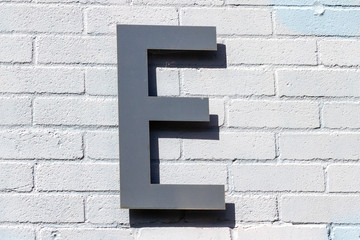 The letter E in steel on a brick wall 