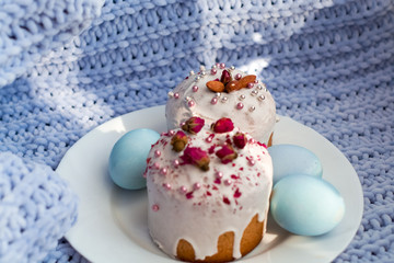 Easter bread, cake and eggs with decor of flowers, beads and nuts. Blue knitted plaid. The concept of the Easter holidays and decor.